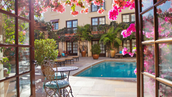 A doorway framed by pink flowers looks out onto the courtyard pool at the Best Western West Hollywood.