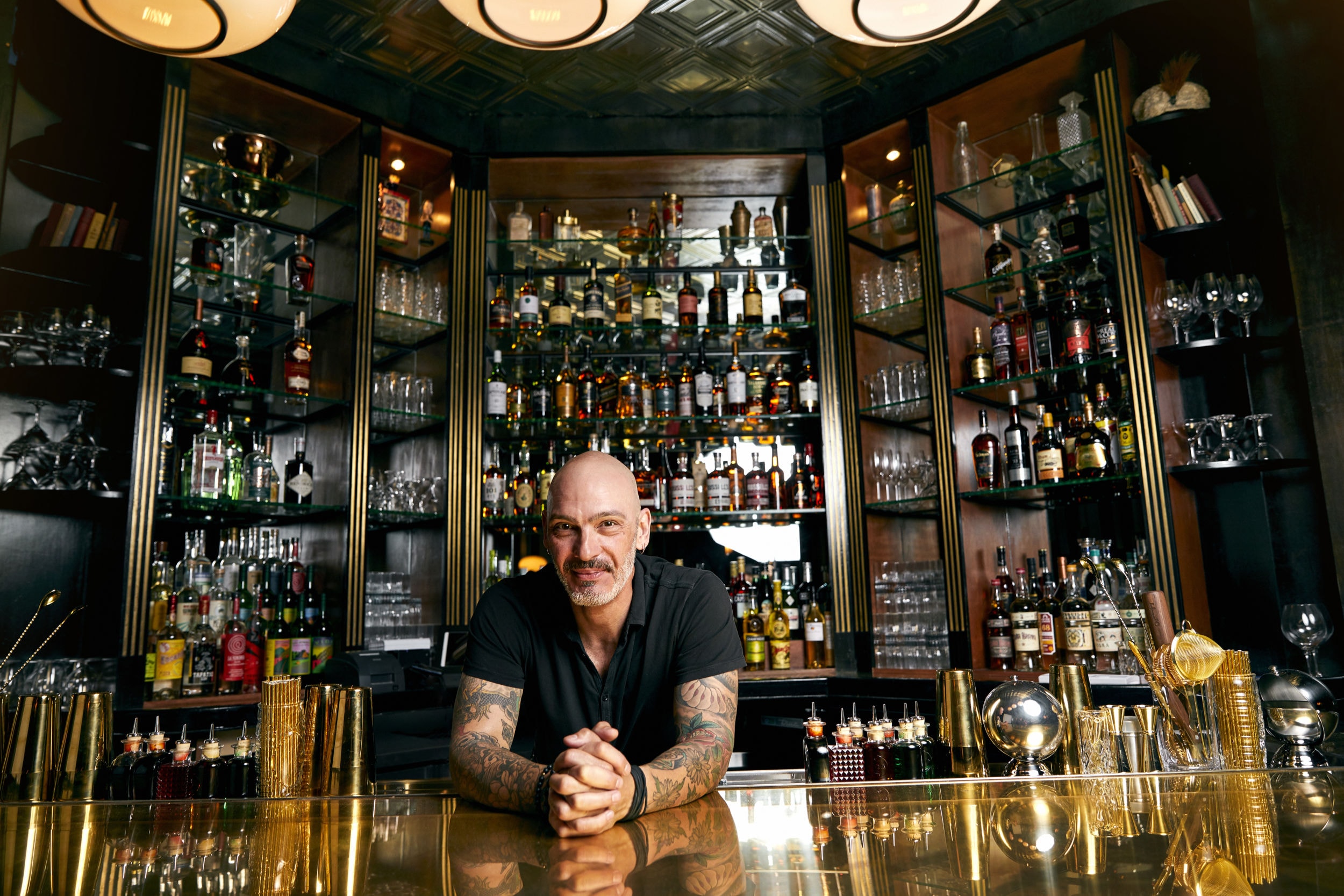 Man leaning on a bar top with a wall of spirits behind him at Employees Only in West Hollywood