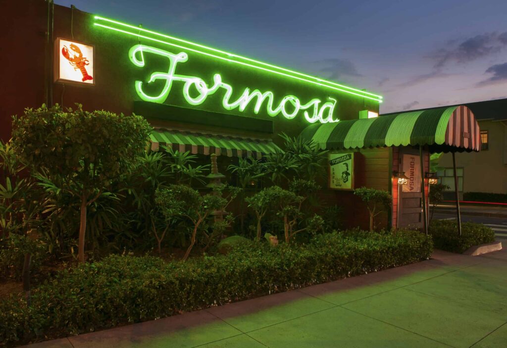 Exterior of the Formosa Cafe in West Hollywood, its sign glowing green neon.