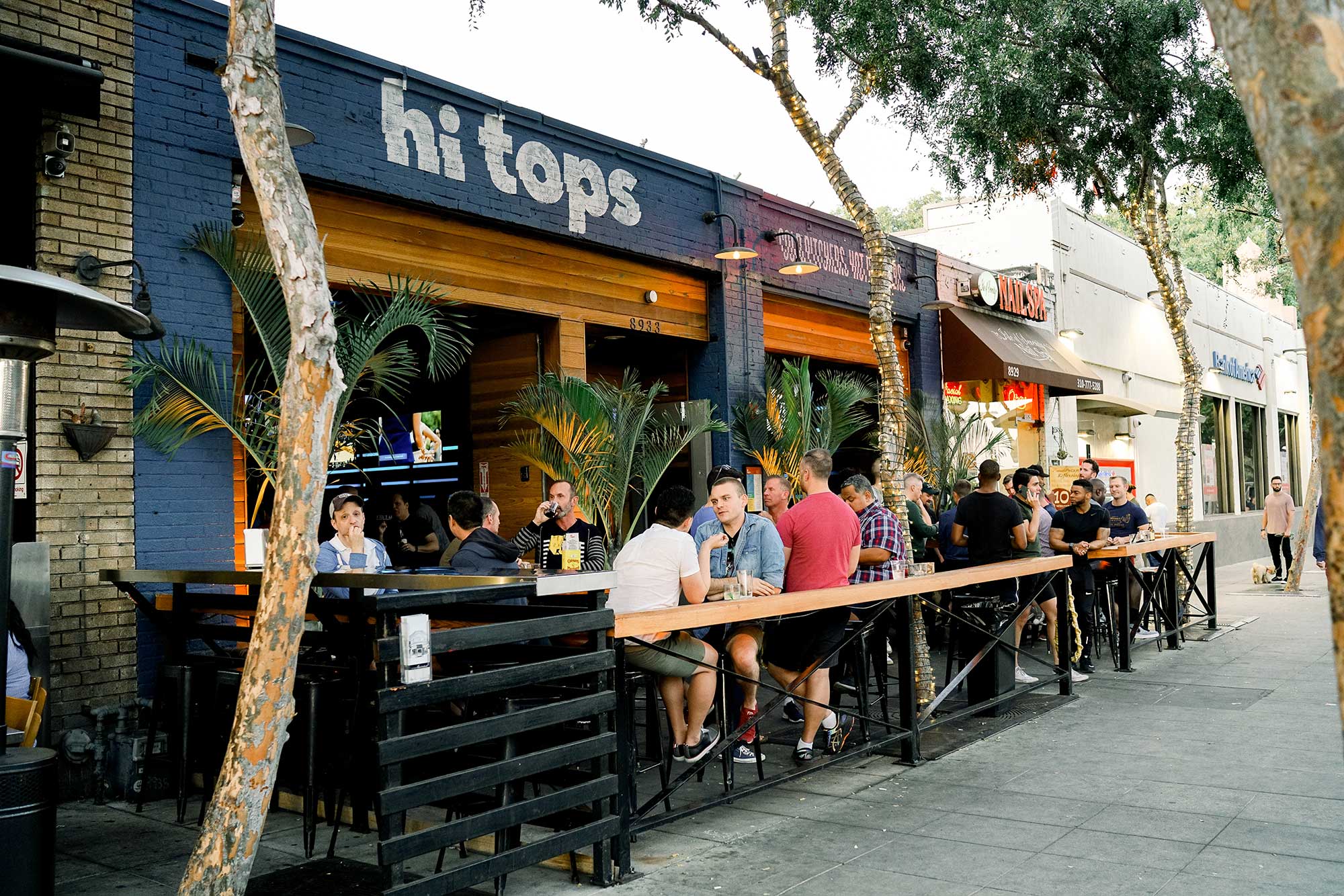 People sit at sidewalk tables at Hi Tops sports bar on Santa Monica Boulevard. West Hollywood, CA.