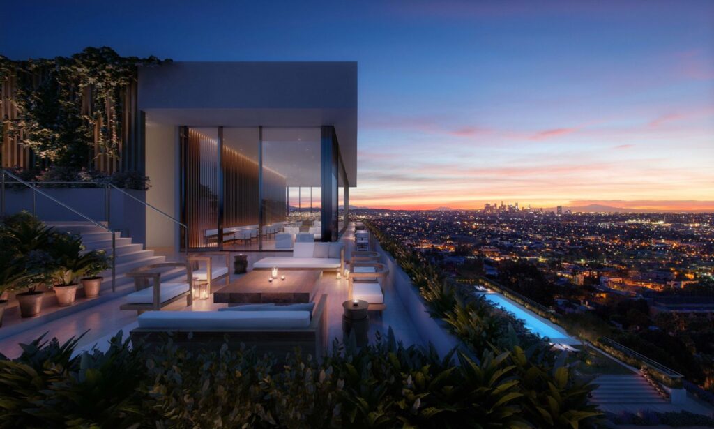 Modern rooftop terrace at The West Hollywood EDITION in CA with lounge seating, candlelit tables, plants and a pool overlooking Los Angeles at sunset, with skyscrapers on the horizon.