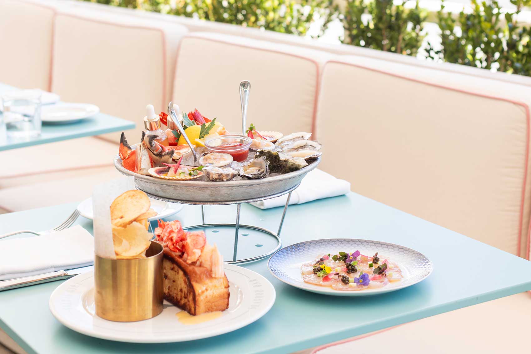 Seafood dishes sit on an outdoor table at Saltie Girl in West Hollywood.