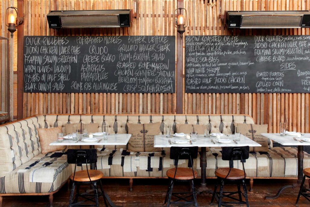 Outdoor seating area with wrap-around booth seating and chalkboards featuring daily specials. Eveleigh, West Hollywood, California.