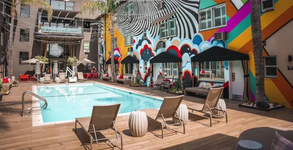 The swimming pool at Hotel Ziggy in West Hollywood, CA, is decorated with murals and lawn chairs.