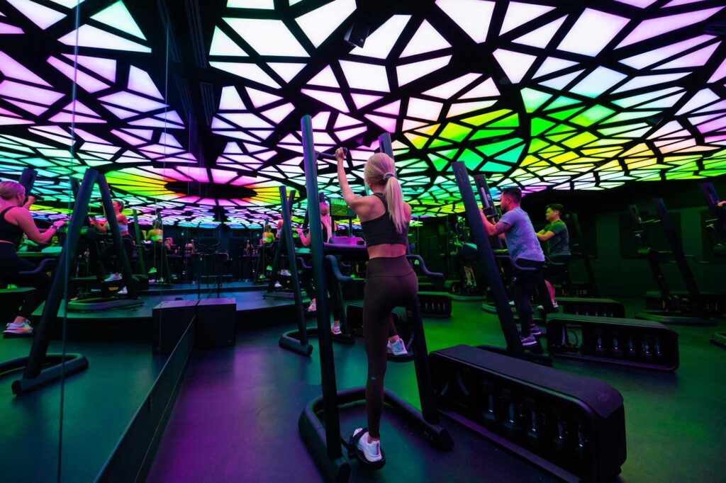 Interior view of a workout room at CLMBR studio in West Hollywood, featuring a ceiling with lighted, multicolored panels.
