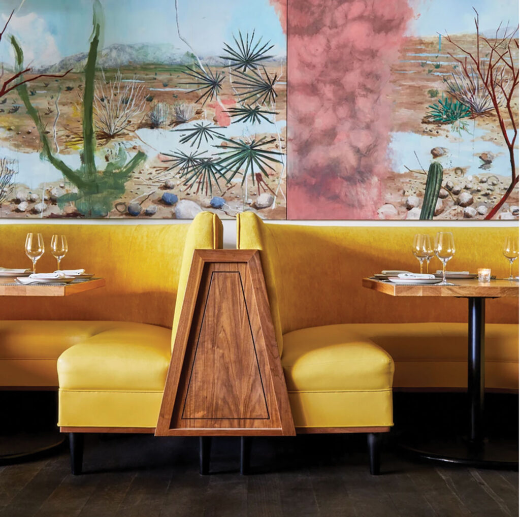 Yellow booth seats are pictured in front of a photograph mural of a desert. Soulmate, West Hollywood, California.