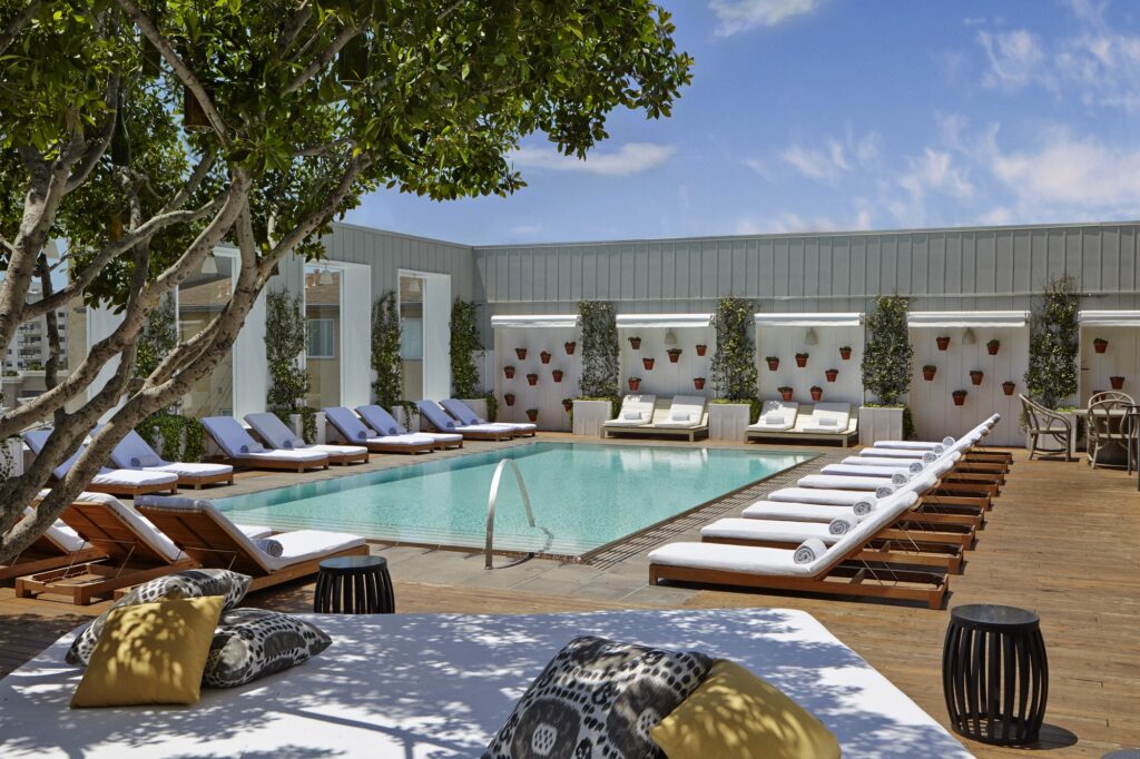 A rooftop pool is lined with white loungers at the Mondrian Los Angeles