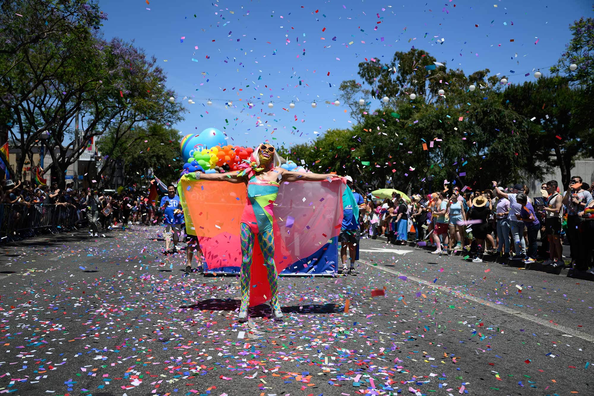 A person in colorful garb poses in the street during a Pride parade in West Hollywood