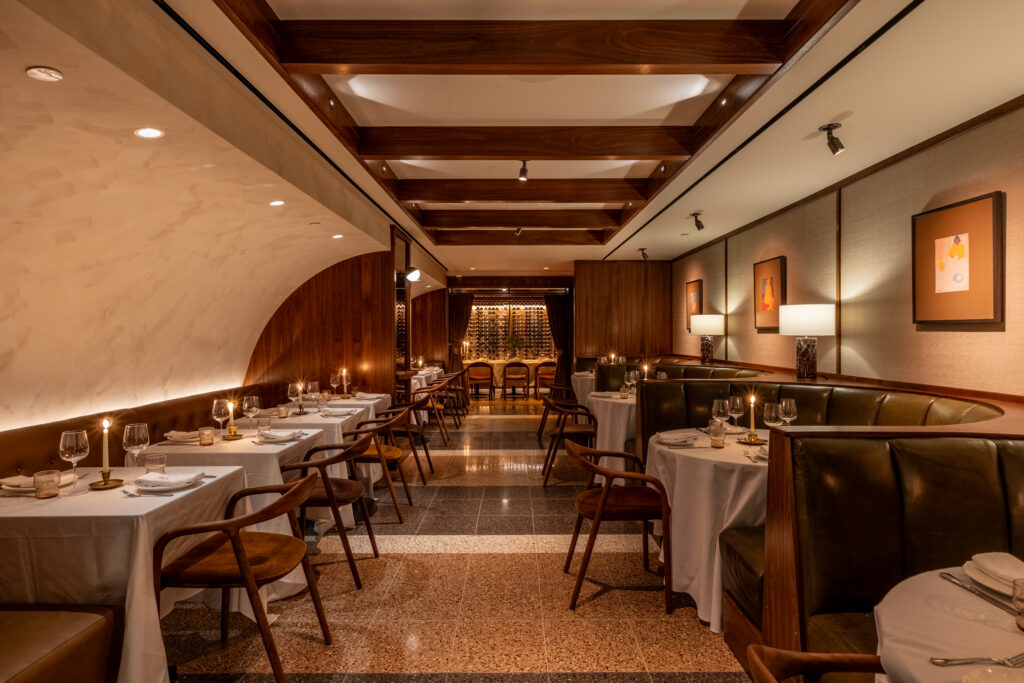 The interior of Stella restaurant in West Hollywood, with leather booths, wooden accents and warm lighting.