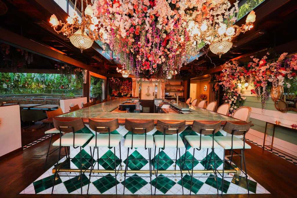 Interior of a restaurant with green-and-white diamond tiles and flowers dangling from the ceiling. Arden, West Hollywood, California.