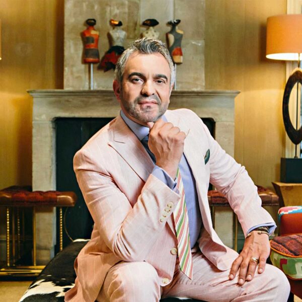 A man in a light-pink suit poses seated with his fist beneath his chin. Martyn Lawrence Bullard. West Hollywood, California.