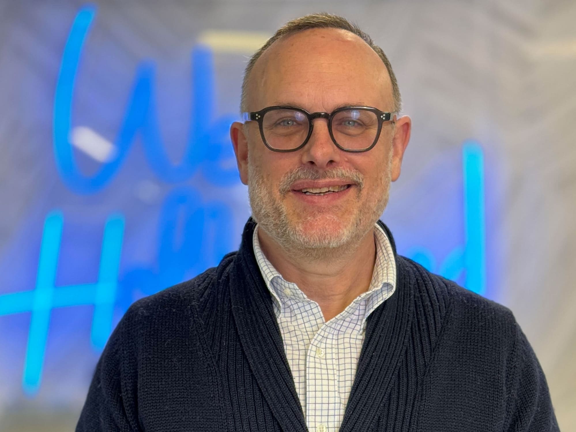 Headshot of Degen Pener, Deputy Editor of The Hollywood Reporter, standing in front of a blue neon West Hollywood sign.