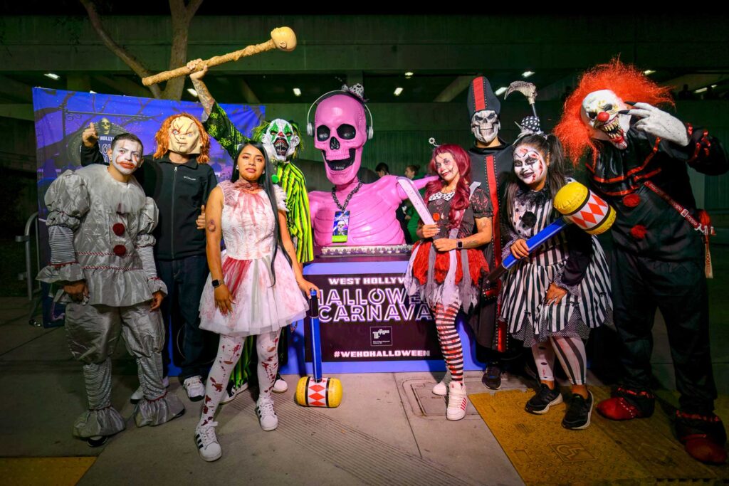 A group of costumed people stands in front of a DJ booth at the West Hollywood Halloween Carnaval.