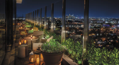 Outdoor rooftop seating overlooking the Los Angeles skyline at night at The West Hollywood EDITION hotel.