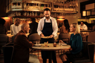 Chef Charbel Hayek serves food to a couple at Ladyhawk restaurant