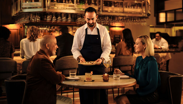 Chef Charbel Hayek serves food to a couple at Ladyhawk restaurant