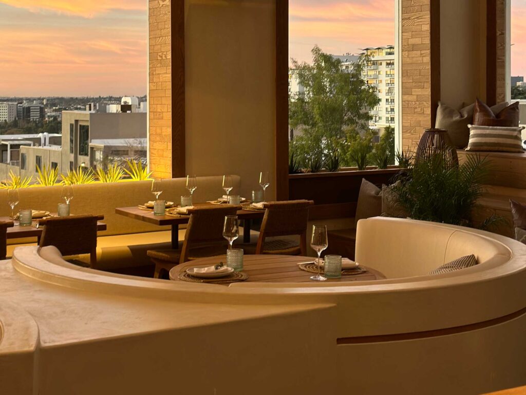 Large arched windows in the dining room of Casa Madera look out over Los Angeles at sunset. Mondrian Hotel, West Hollywood, California.
