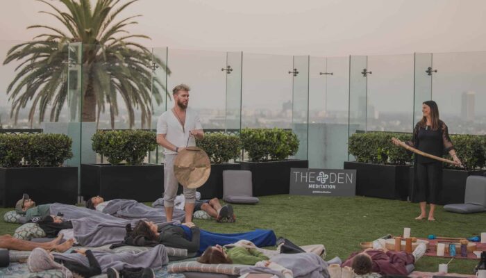 A man with a pair of cymbals walks among people meditating on the rooftop of The London Hotel in West Hollywood, California.