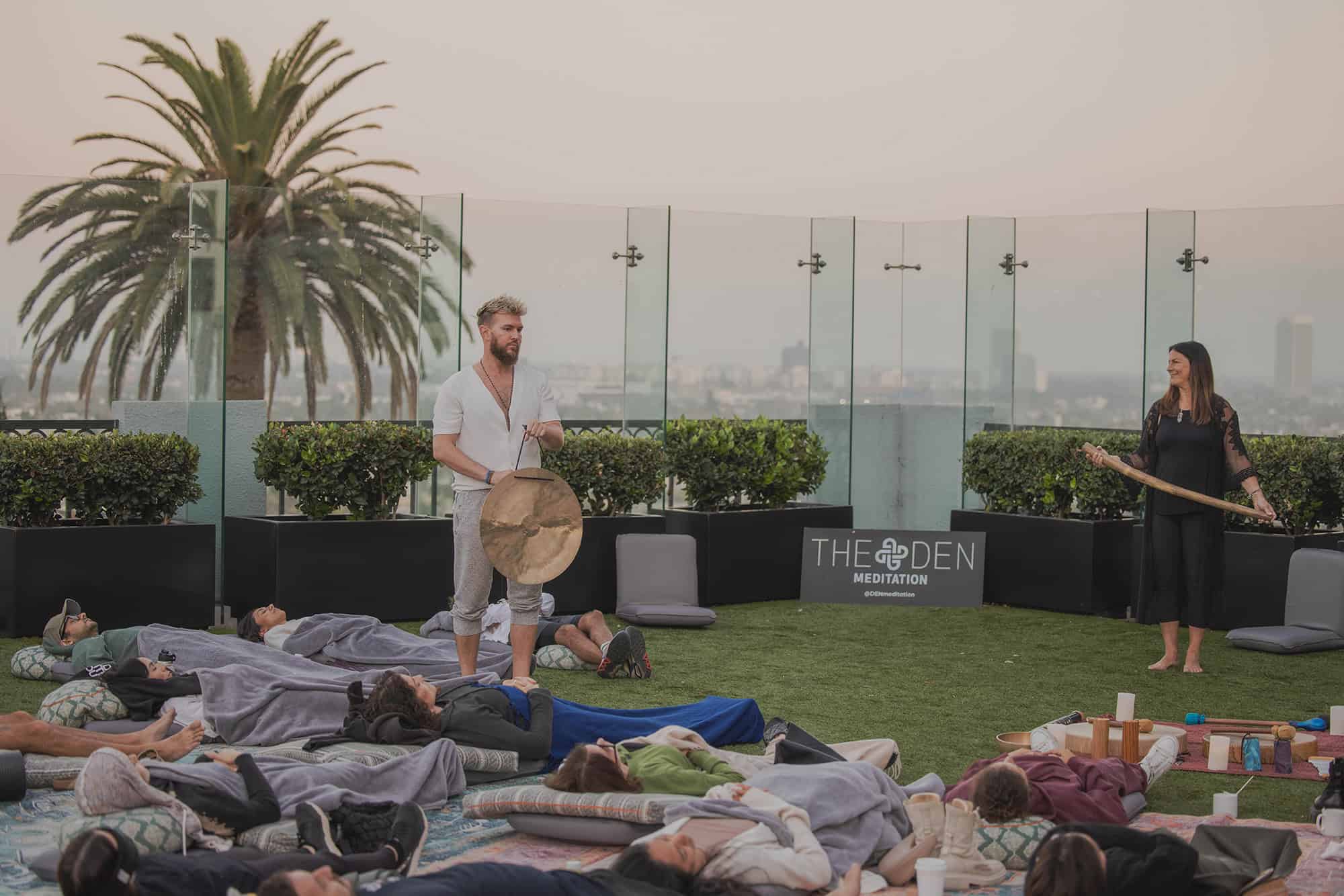 A man with a pair of cymbals walks among people meditating on the rooftop of The London Hotel in West Hollywood, California.