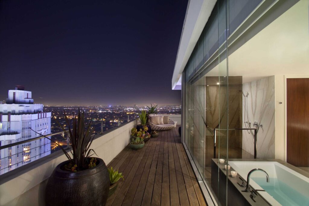 Rooftop terrace at the Andaz West Hollywood featuring Los Angeles skyline views, outdoor seating, potted plants, and a luxurious bathtub. West Hollywood, CA