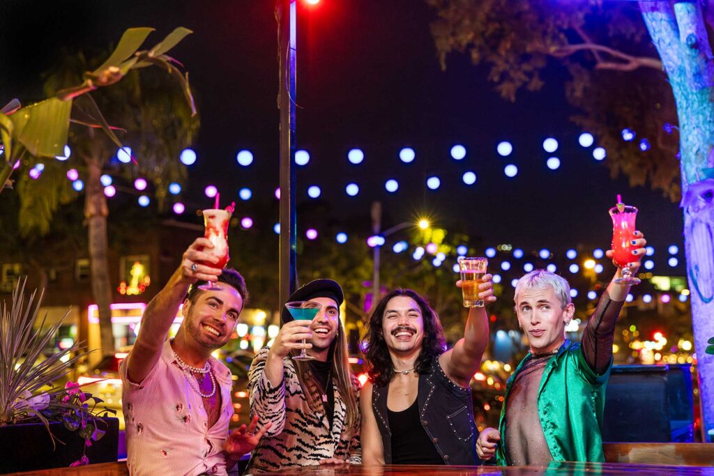 Four friends raise drinks at a bar in West Hollywood's Rainbow District.