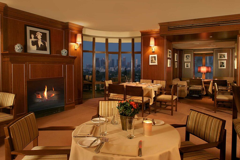 Interior of the Tower Bar at the Sunset Tower Hotel, with floor-to-ceiling windows showing the Los Angeles skyline at dusk.