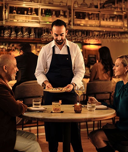 Chef Charbel Hayek serves food to a couple at Ladyhawk restaurant