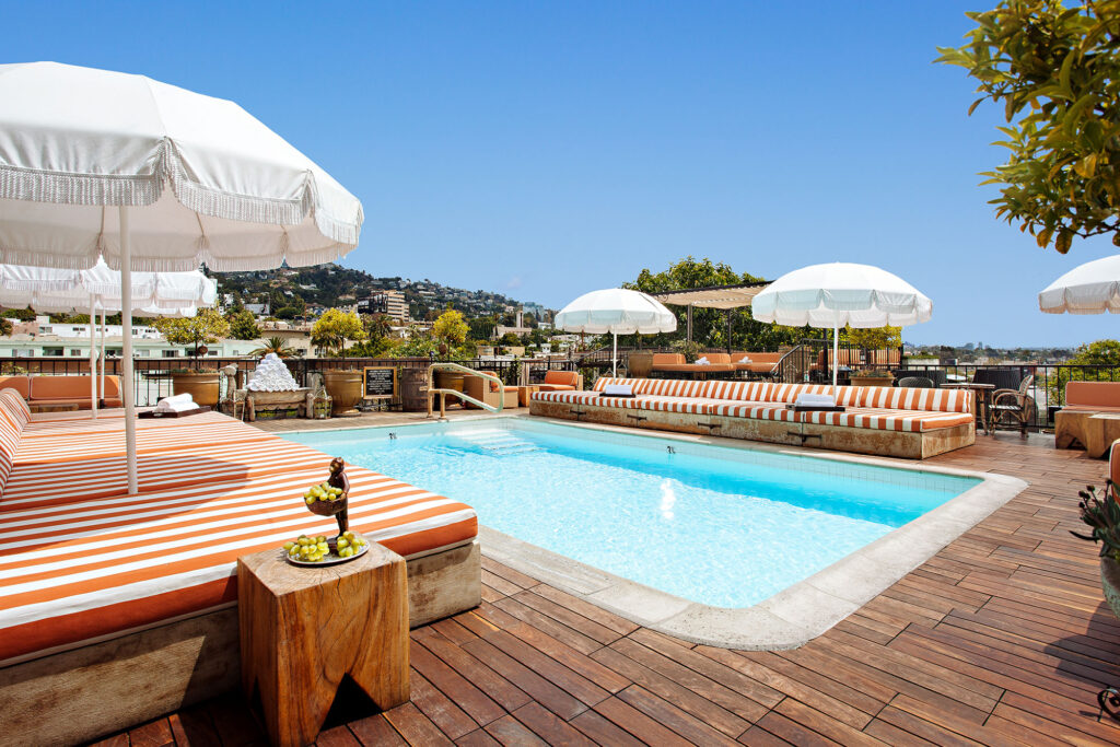 Rooftop pool at Petit Ermitage in West Hollywood, with white umbrellas and red-and-white striped loungers