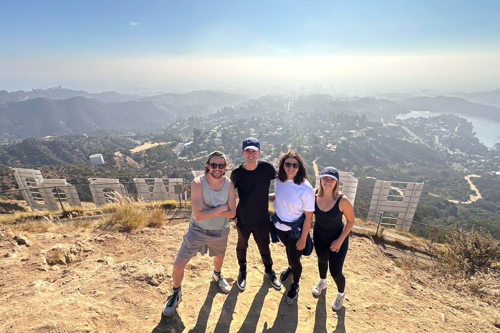 A group of people stands behind the Hollywood Sign
