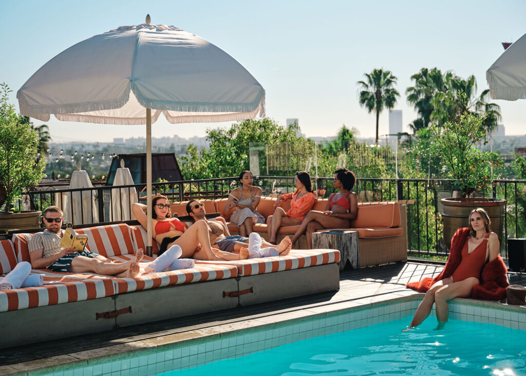 People relax on striped sofas next to the rooftop pool at the Petit Ermitage hotel