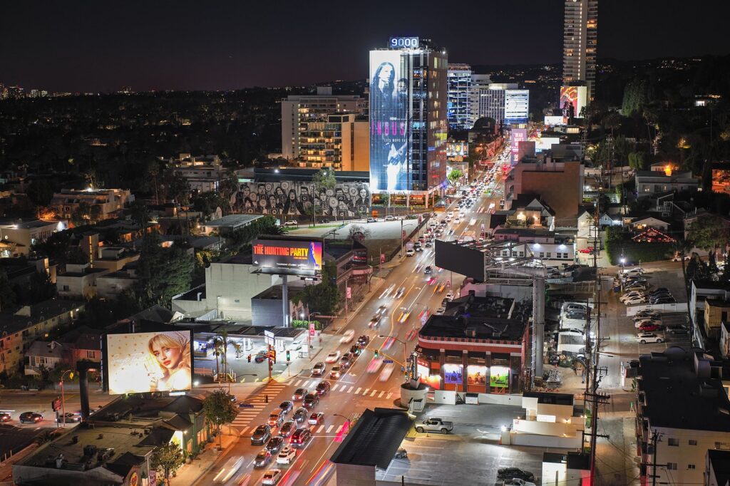 Aerial view of Sunset Strip in West Hollywood, CA, at night with illuminated billboards, traffic and buildings.