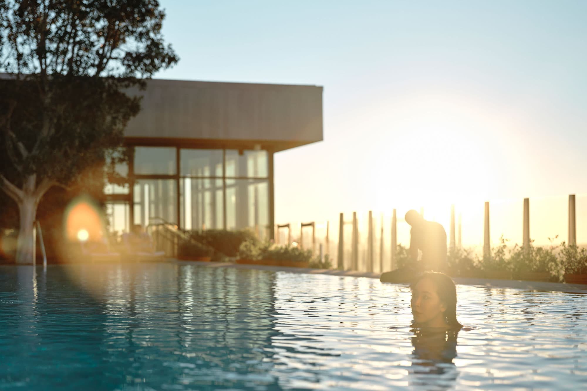 A woman swims in the rooftop pool at The West Hollywood EDITION at sunset.