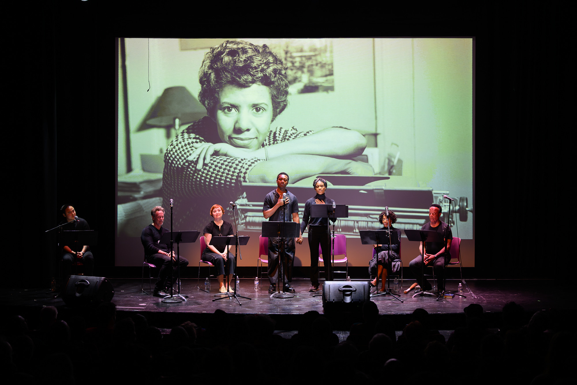 Performers on stage with a black and white photo backdrop during the WeHo Pride Arts Festival