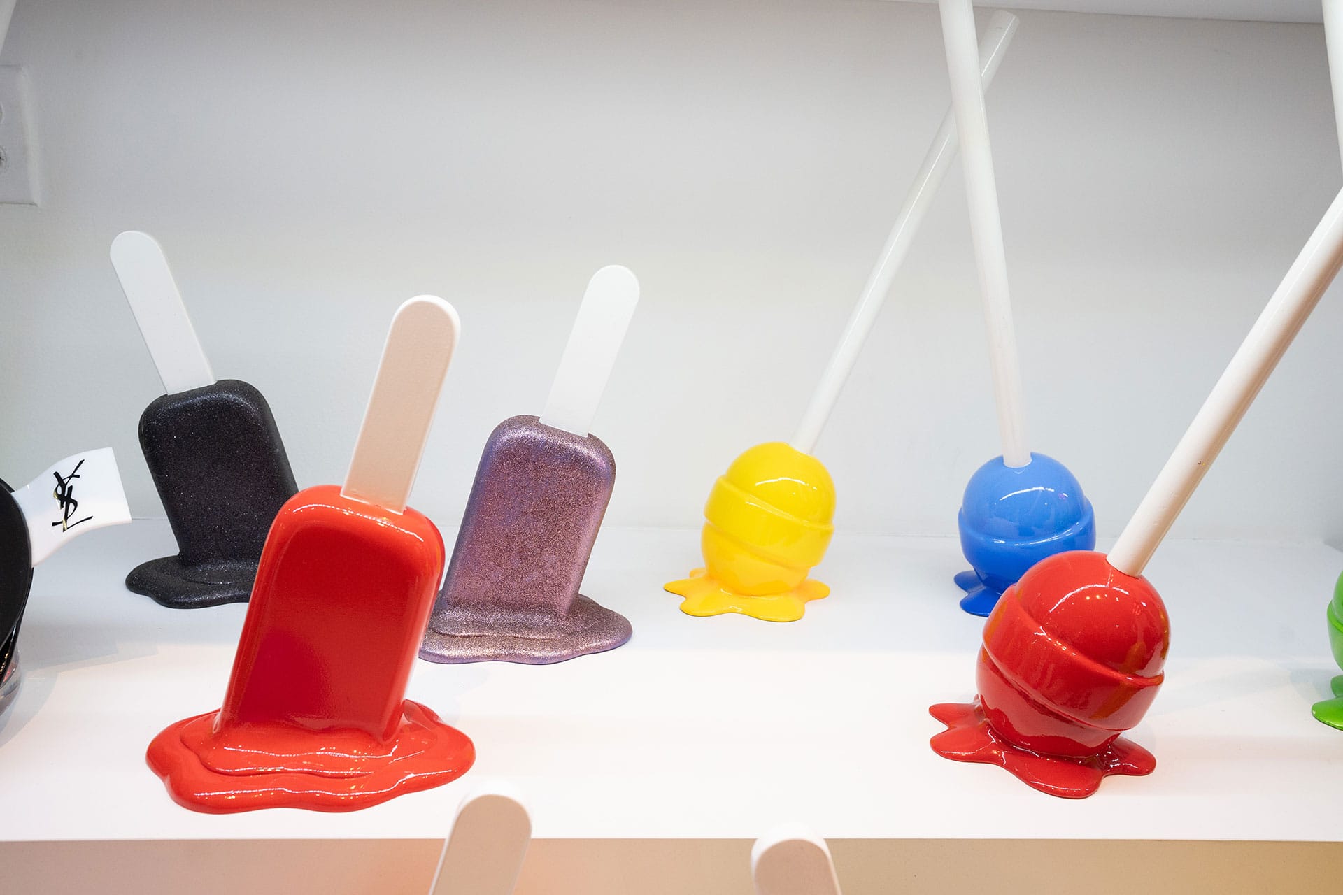 Colorful sculptures of melting popsicles and lollipops are displayed on a white surface, at Duroque West Hollywood.