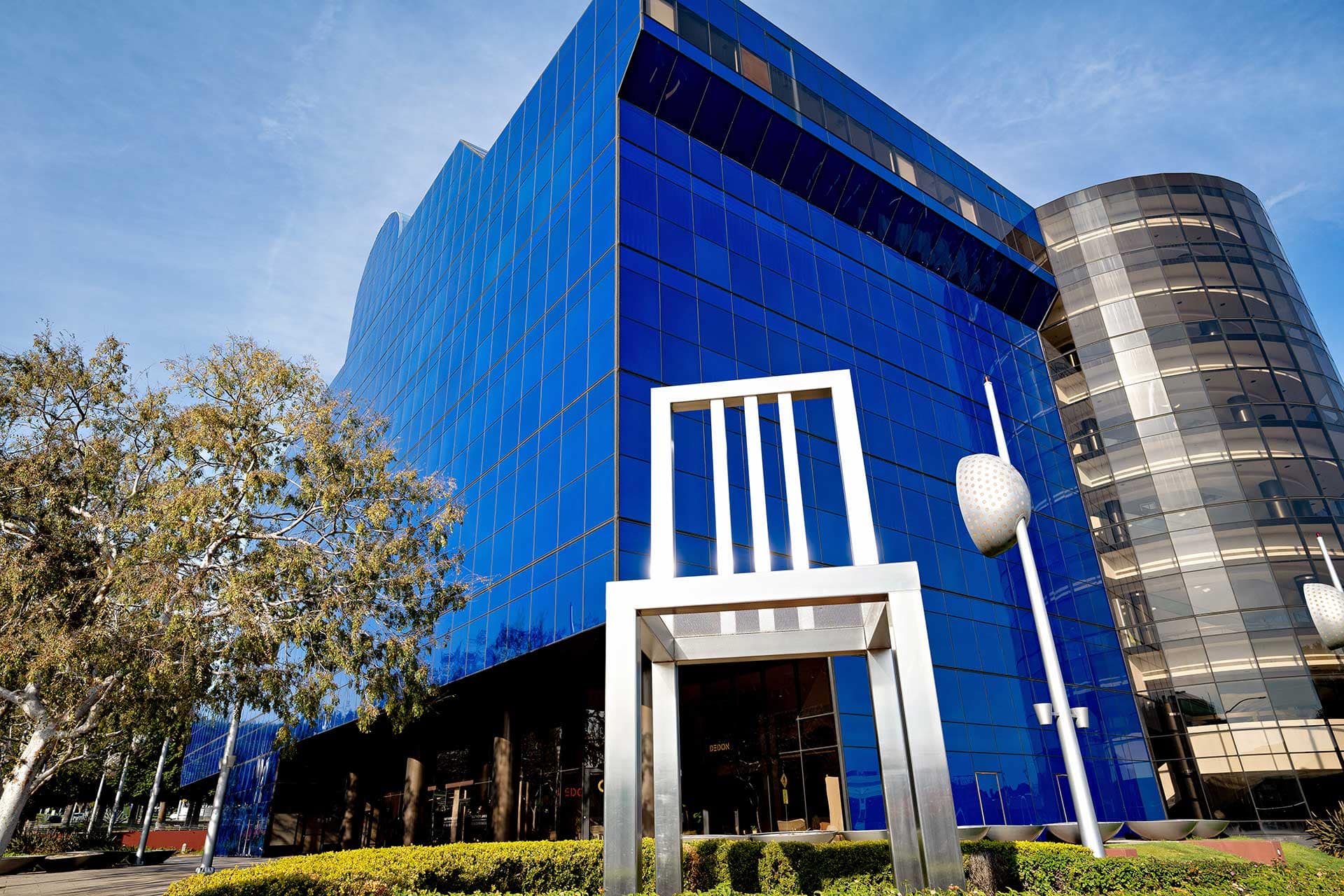 A giant steel chair stands in front of a blue building at the Pacific Design Center in West Hollywood, CA.